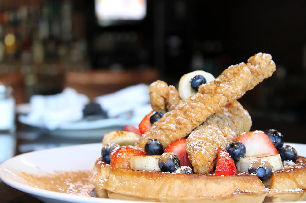 Chicken and waffles at The Edge — crispy fried chicken over a golden waffle with fresh berries and banana