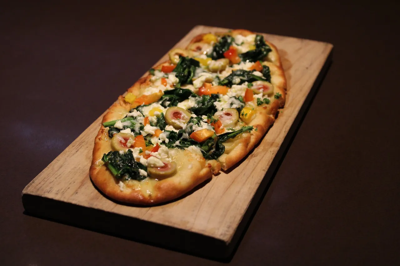 Greek flatbread at The Edge — feta, spinach, peppers, onions, black olives and mozzarella on a wooden board