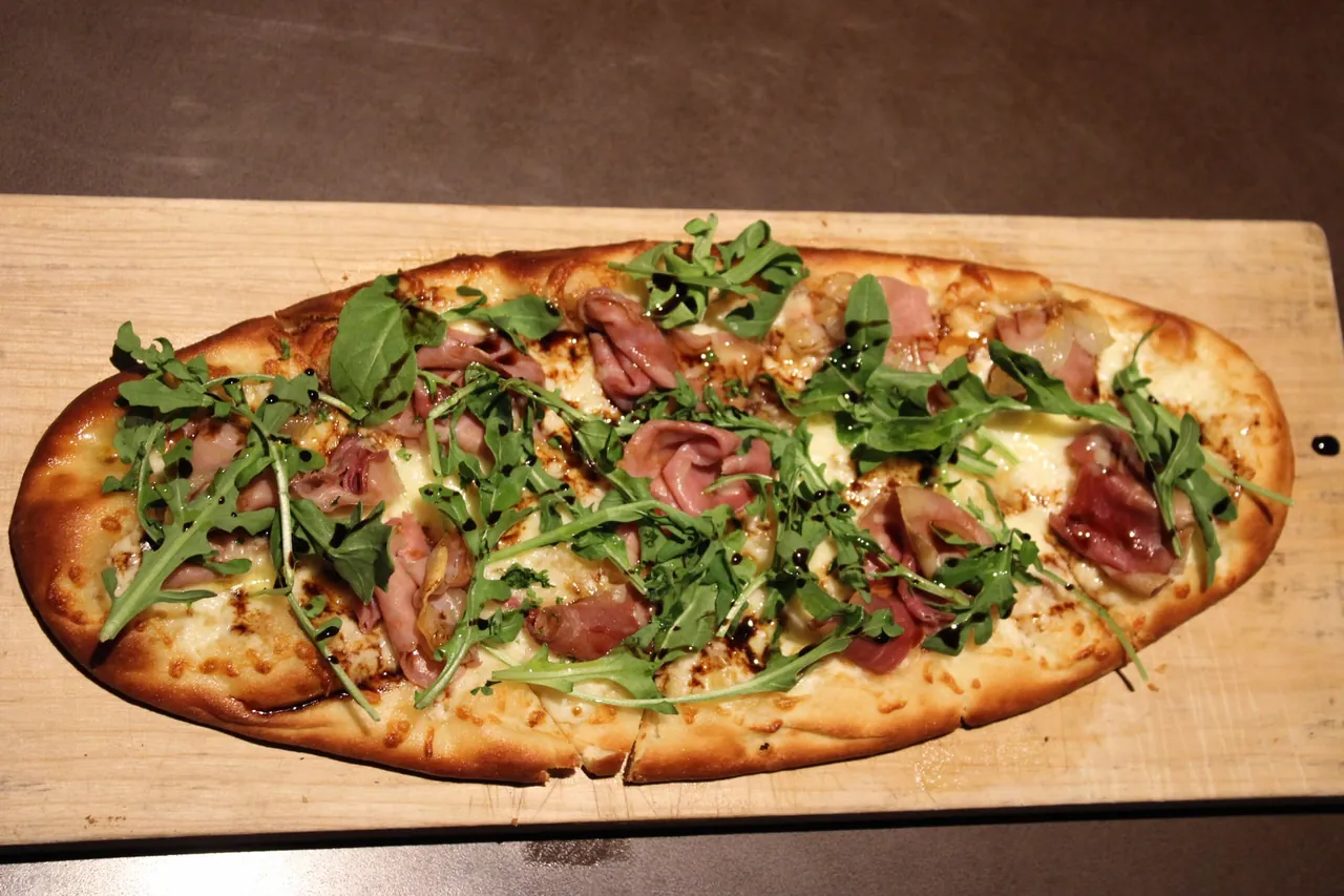 Prosciutto and arugula flatbread at The Edge — prosciutto, mozzarella and fresh arugula on a wooden board