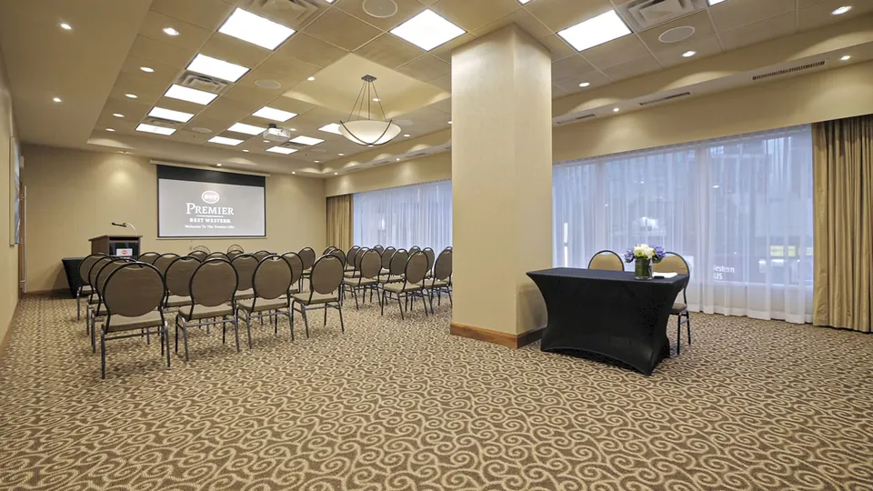 Meeting room set up theatre-style with projector screen and Best Western Premier branding at Chateau Granville