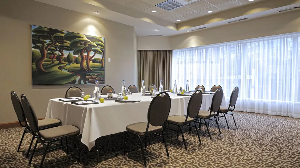 Boardroom-style meeting setup with long table, water bottles and West Coast landscape art at Chateau Granville