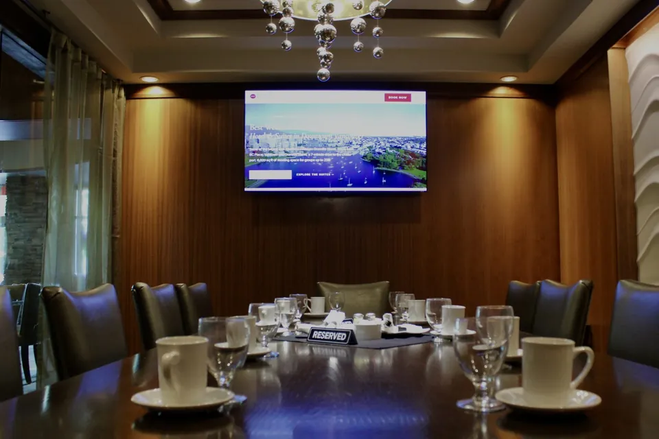 Cambie Room at Chateau Granville set for twelve around a single table, with the 65-inch TV on the walnut wall