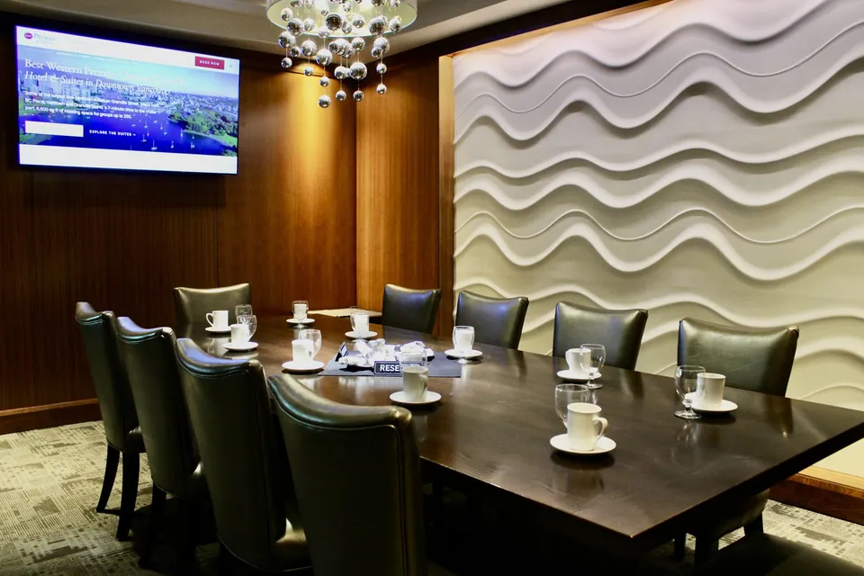 The Cambie Room at Chateau Granville, the 65-inch TV and the sculpted wave feature wall above a table set for twelve