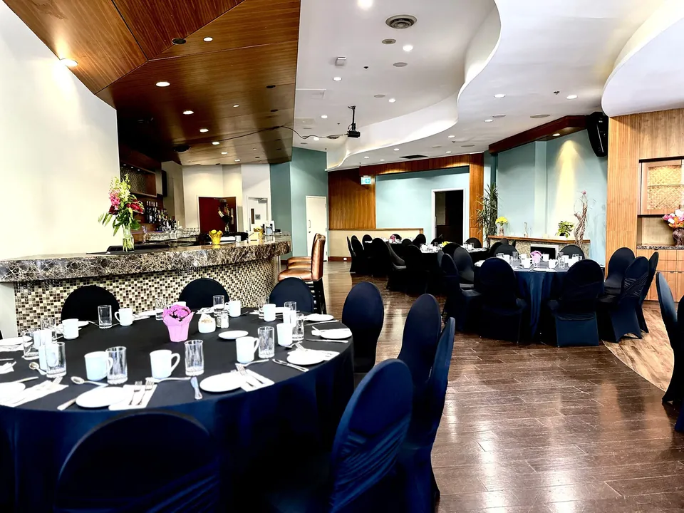Capilano Room set for a banquet at Chateau Granville, with linen-draped round tables beside the room's marble and mosaic-tiled bar