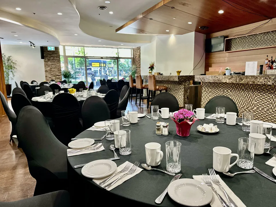 Capilano Room banquet setup at Chateau Granville — round tables, the marble bar, and street-facing Granville Street windows