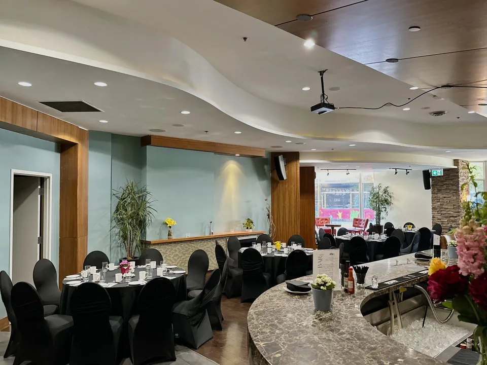 Capilano Room at Chateau Granville — the curved marble bar and banquet tables beneath the room's wave-form ceiling