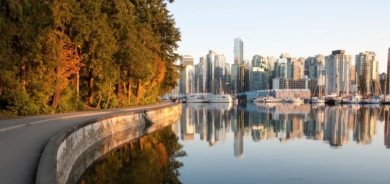 Vancouver seawall in fall colour, with the downtown skyline and marina reflected in calm water